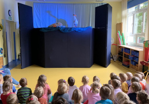Dzieci siedzą i oglądają przedstawienie teatralne.