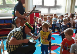 Dzieci dotykają instrumentu i grają na nim.