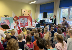 Dzieci maszerują i śpiewają pieśni patriotyczne.