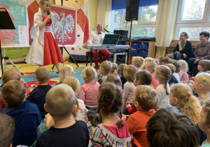 Pani śpiewa dzieciom pieśni patriotyczne.