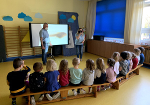 Dzieci oglądają prezentację dotyczącą rozwoju żaby.
