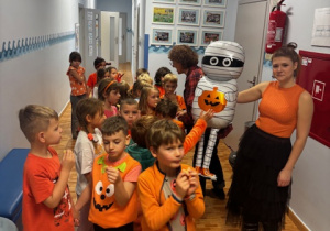 Dzieci pozują do zdjęcia z balonowym kościotrupem i panią nauczycielką.