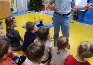 Pan edukator pokazuje dzieciom naklejki.