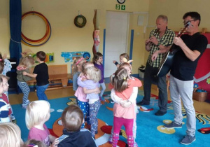 Dzieci tańczą w parach przy dźwiękach gitary.