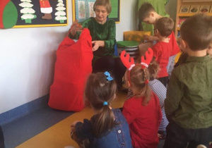 Pani nauczycielka wyciąga z worka prezenty dla dzieci od Świętego Mikołaja.
