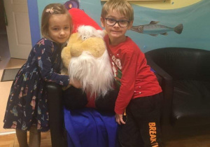 Dzieci przytulają się do maskotki świętego Mikołaja.