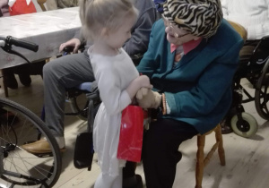 Dziewczynka wręcza Seniorom z Domu Opieki Społecznej prezenty.