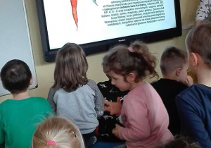 Dzieci oglądają prezentację multimedialną dotyczącą marchewki.