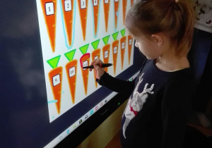 Dziewczynka zaznacza na tablicy interaktywnej marchewki według instrukcji "zaznacz co drugą marchewkę".
