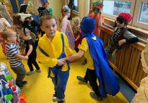 Chłopcy w stroju Minionka i Superbohatera tańczą na balu karnawałowym.