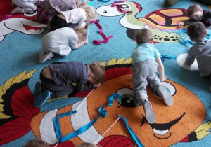 Dzieci czworakują po dywanie.