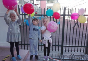Dzieci stoją i trzymają w ręku balony.