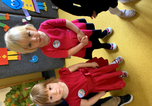 Dziewczynki prezentują swoje odznaki z okazji pasowania na przedszkolaka.