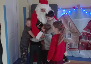 Dzieci przytulają sie do Świętego Mikołaja.