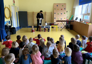Dzieci słuchają jak pan muzyk gra na instrumentach perkusyjnych.