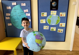 Chłopiec prezentuje globus oraz dobre zachowania dla Ziemi.