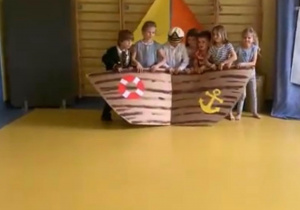 Dzieci trzymają statek zrobiony z papieru.