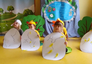 Dzieci są schowane za papierowymi jajkami.