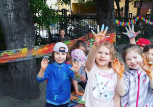 Dzieci pokazują ręce pobrudzone farbą.