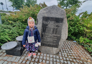Dziecko stoi przy pomniku pamięci Powstania Warszawskiego.