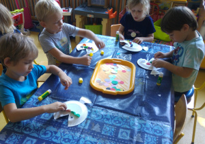 Dzieci wyklejają łuski rybkom z papierowych talerzyków.