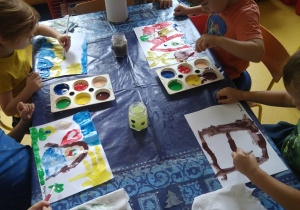 Dzieci malują farbami swoje wspomnienia z wakacji.