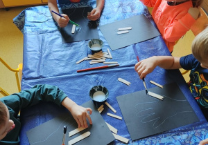 Dzieci tworzą pracę plastyczną "Rentgen dłoni" z patyczków kosmetycznych.