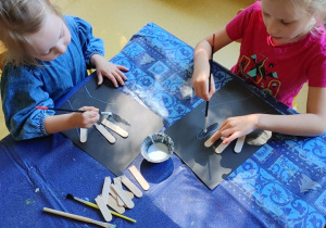 Dzieci tworzą pracę plastyczną "Rentgen dłoni" z patyczków kosmetycznych.