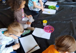 Dzieci malują farbami portret.