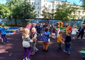 Dzieci tańczą na przedszkolnym placu zabaw.