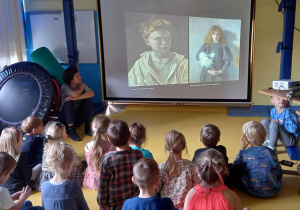 Dzieci oglądają portrety na dużym ekranie.