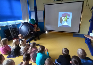 Dzieci oglądają portret na dużym ekranie.
