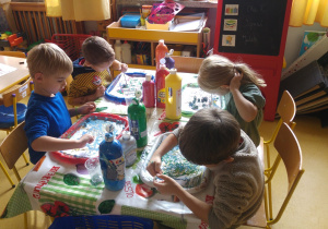 Dzieci malują abstrakcję z pomocą szklanych kulek i farby.
