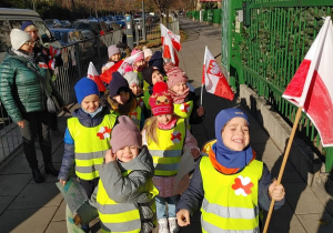 Dzieci na idą na spacer niepodległościowy z mapą i flagami.