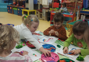Dzieci wykonują pracę plastyczną z użyciem plasteliny.