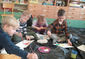 Dzieci malują farbami podczas warsztatów plastycznych.