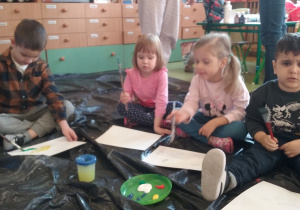 Dzieci malują farbami podczas warsztatów plastycznych.
