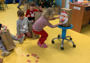 Dzieci wkładają pierniczki do pudełka dla Mikołaja w podziękowaniu za prezenty.