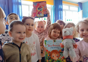 Gabrysia i Natalka pokazują przyniesione książki, towarzyszy im grupa dzieci.