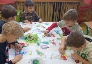 Dzieci wyklejają szablon choinki kółeczkami z plasteliny.
