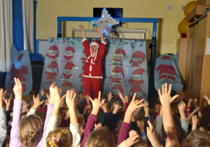 Teatrzyk. Dzieci razem z panią Mikołajową podnoszą ręce do góry.