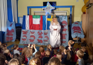 Teatrzyk. Dzieci oglądają aktorkę przebraną za świętą Łucję.