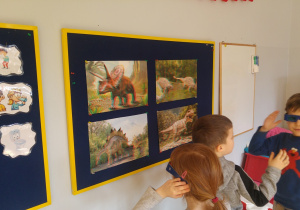 Dzieci oglądają zdjęcia dinozaurów w okularach 3D.