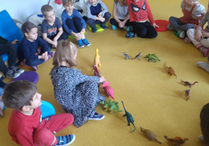 Dziewczynka szereguje dinozaury od największego do najmniejszego.