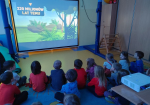 Dzieci oglądają film o dinozaurach.