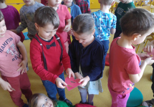 Dzieci szukają pary na podstawie połówki wyciętego serduszka.