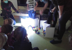 Dzieci sprawdzają jak działają lampiony z pomocą latarki.