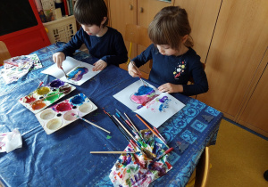Dzieci tworzą pracę plastyczną- malują motyle farbami.
