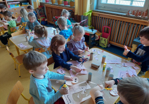 Dzieci tworzą świnki z papieru.