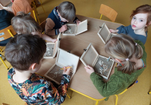 Dzieci odnajdują szkielety dinozaurów w pudełkach z piaskiem.